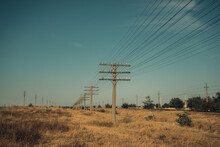 Wood Pole And Crossarms Support Electrical Wires In Rural Setting, Against The Blue Sky