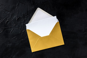 Greeting card in a golden envelope mockup, shot from above on a black background with copy space