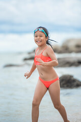 Wall Mural - child relaxing on the beach against sea and sky background. summer vacation and travel concept. happy little girl running on the beach.