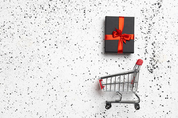 Shopping trolley with gift box and cope space on white cement background