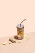 Immune Strengthening Drink. Ginger water in stylish jar with metal straw on geometric paper background and ginger slices, isometric view