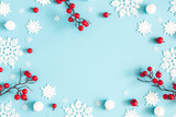 Fototapeta Mapy - Christmas or winter composition. Snowflakes and red berries on blue background. Christmas, winter, new year concept. Flat lay, top view, copy space