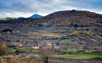 Wall Mural - Serene Spanish rural landscape, with distant colorful village and green mountains.