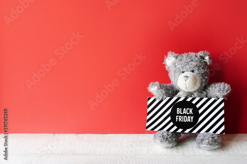Fotografía gray teddy bear with sign black friday on red background, copy space