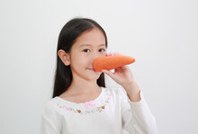 Funny Face Asian Little Girl Making Long Nose With Carrot On White Background