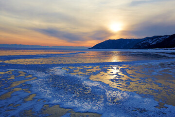 Beautiful sunset on the frozen lake Baikal. Winter landscape in Russia.