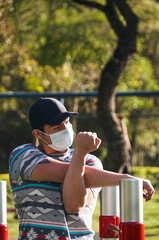 Young man wearing face mask stretching his muscles before starting his exercise routine