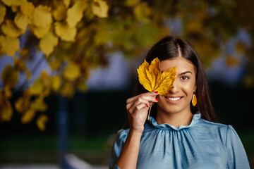 beautiful young woman laying and smiling on the oak and maple leaves in the park.