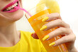 Young woman drinking pineapple juice with joy. Trendy manicure with yellow nail polish on a long form.