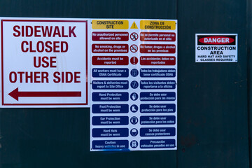 Astoria, Queens, New York City - May 18, 2020: Several signs at a construction site warn passerby's that the sidewalk is closed and dangerous. There's also a Spanish version along with symbols.