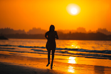 Wall Mural - Adorable happy little girl on white beach at sunset.