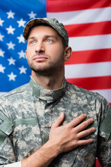 Wall Mural - patriotic military man pledging allegiance near american flag on blurred background