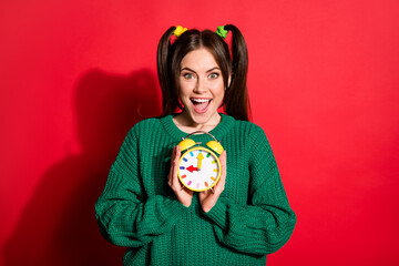 Canvas Print - Portrait of young beautiful excited happy positive female hold clock look camera isolated on red color background