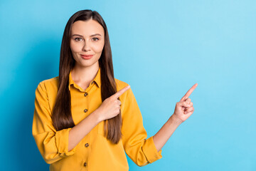 Sticker - Portrait of sweet nice brunette lady pointing empty space wear yellow cloth isolated on blue color background