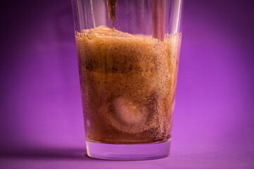 Wall Mural - detail of fizzy and carbonated cola drink on purple background