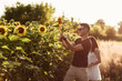 © Andriy Medvediuk - Beautiful couple having fun in sunflowers field. A man and a woman in love walk in a field with sunflowers, a man hugs a woman. selective focus