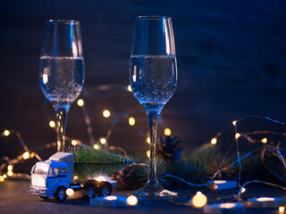 Wall Mural - Celebrate Christmas, two glasses of sparkling champagne at night on a table lit with garlands and colored lights