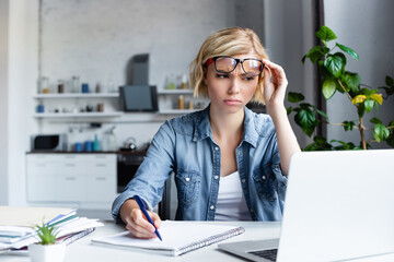 Wall Mural - confused blonde woman making notes in notebook