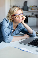 Wall Mural - bored blonde woman in eyeglasses working from home