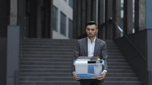 Businessman gets fired and walking near office center with box documents. Lost His Job. Unemployment rate growing due pandemic. Male office worker in despair lost job