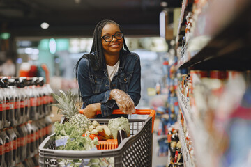 African woman with shopping cart. Girl in a supermarket.