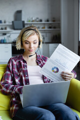 Wall Mural - young blonde woman in headphones having online conference and showing graphs