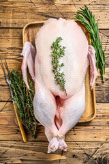 Raw whole farm duck with herbs. wooden background. Top view