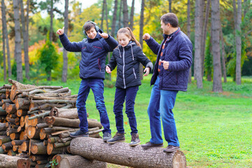 Wall Mural - family relaxing outdoor in autumn city park, happy people together, parents and children, they standing on a log, playing, talking and smiling, beautiful nature