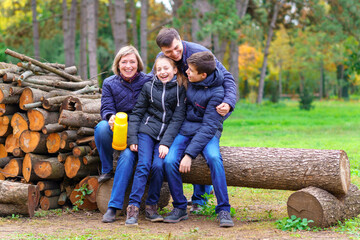 Wall Mural - family relaxing outdoor in autumn city park, happy people together, parents and children, they talking and smiling, beautiful nature