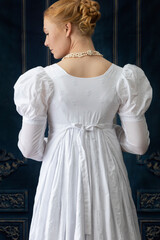 A Regency woman wearing a white muslin dress standing alone in a room