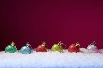 Christmas balls in snow against pink background with copy space. New Year and Xmas greeting