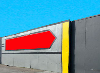 Wall Mural - Huge blank red arrow on side of industrial park wall. Blue sky. Copy space.