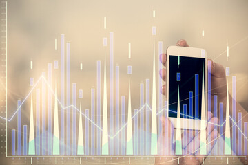 Double exposure of forex graph sketch hologram and woman holding and using a mobile device. Stock market concept.