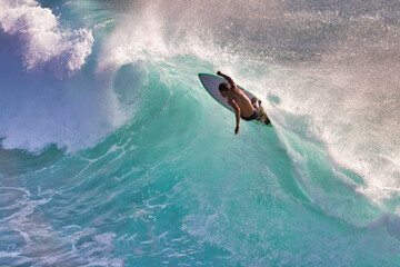 Hard charging silhouetted surfer on a gorgeous aqumarine wave on Maui.