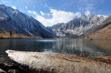 Fototapeta Do pokoju - Pretty fall colors, snow-capped mountains, a big log and reflections at Convict lake on a cloudy day in the autumn
