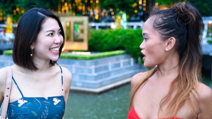 Canvas Print - Two beautiful young asian women talking and relaxing walking along city streets