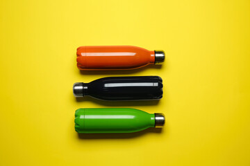 Wall Mural - Modern thermo bottles on yellow background, flat lay