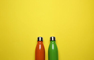 Wall Mural - Modern thermo bottles on yellow background, flat lay. Space for text