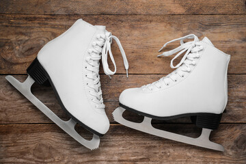 Wall Mural - Pair of white ice skates on wooden background, flat lay