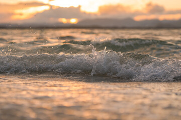 bubbles at the top of the wave on the beach with the sunset sky