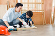 © JuYochi - Father, a carpenter, teaches his son to hammer nails.