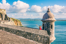 San Juan Puerto Rico Travel Happy Asian Tourist Woman Excited With Open Arms In Happiness At Watch Tower Of Castillo San Felipe Del Morro Summer Cruise Vacation.