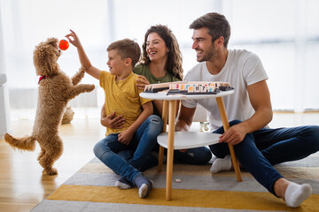 Wall Mural - Happy family having fun time, playing together at home with dog