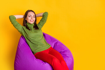 Poster - Photo of adorable lady sit bean bag hands behind head wear green sweater red pants isolated yellow color background