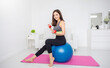© paulaphoto - Portrait of young asian attractive fitness woman holding dumbbell sitting on big ball at home. Sport ware girl workout with strong beautiful fit body shape, Asia lifestyle with copy space