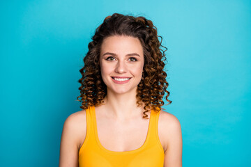 Wall Mural - Photo of pretty stunning young girl beaming toothy smiling look camera wear yellow singlet isolated blue color background