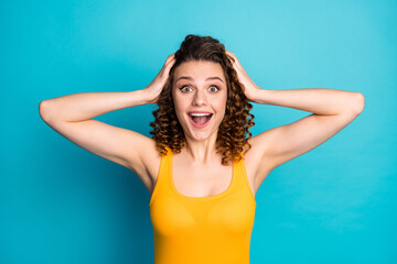 Poster - Photo of pretty excited student girl hands head open mouth amazed look camera wear yellow singlet isolated blue color background