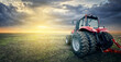 Agricultural tractor working in the field at sunset background