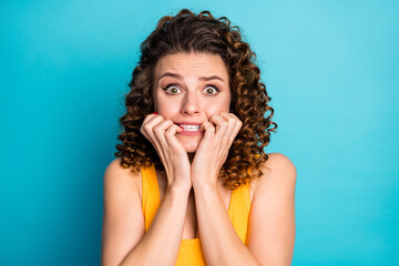 Wall Mural - Photo of pretty nervous student girl gnaw nails scared look camera wear yellow tank-top isolated blue color background