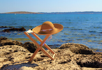 A hat on a chair on the beach. Nobody present.